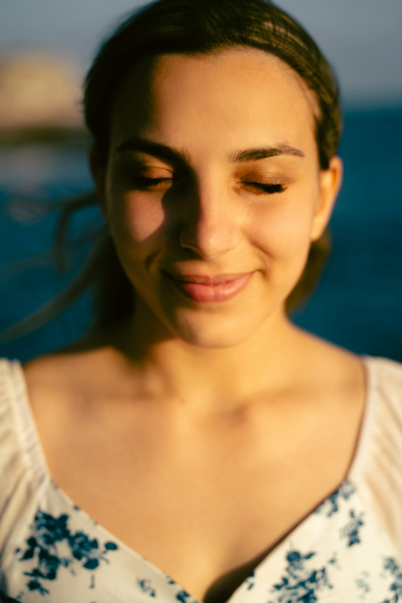 Mulher serena, de olhos fechados, à luz do sol
